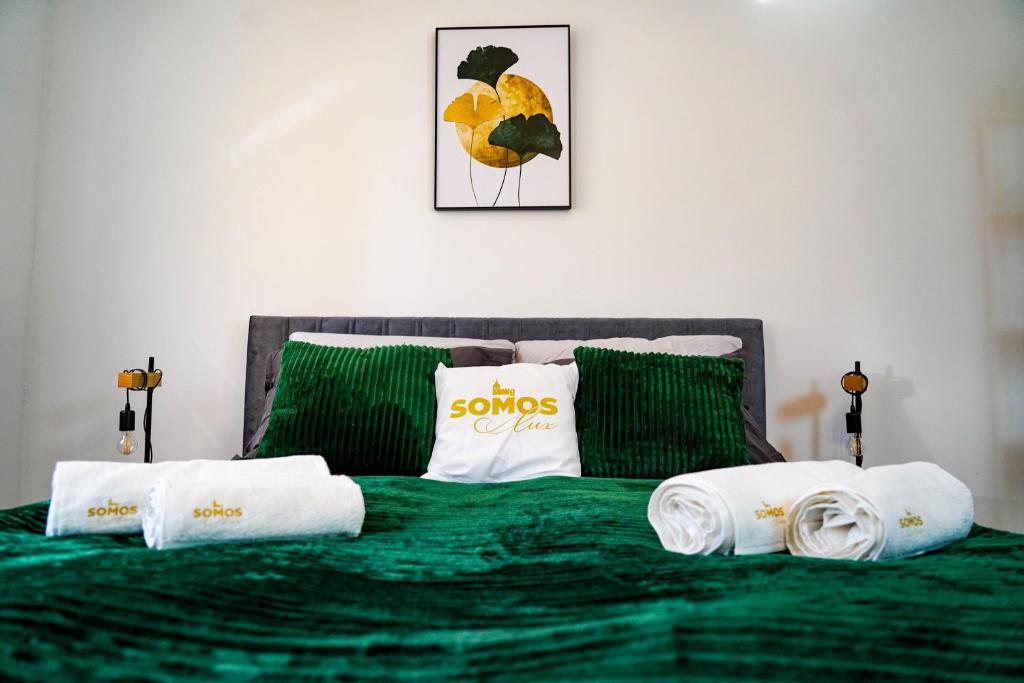um quarto com uma cama verde e toalhas em Somos Lux Vendégház em Somoskőújfalu