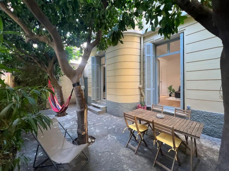 une table et des chaises en bois à côté d'un arbre dans l'établissement Les Orangers - 3 Pièces avec terrasse arborée, à Nice