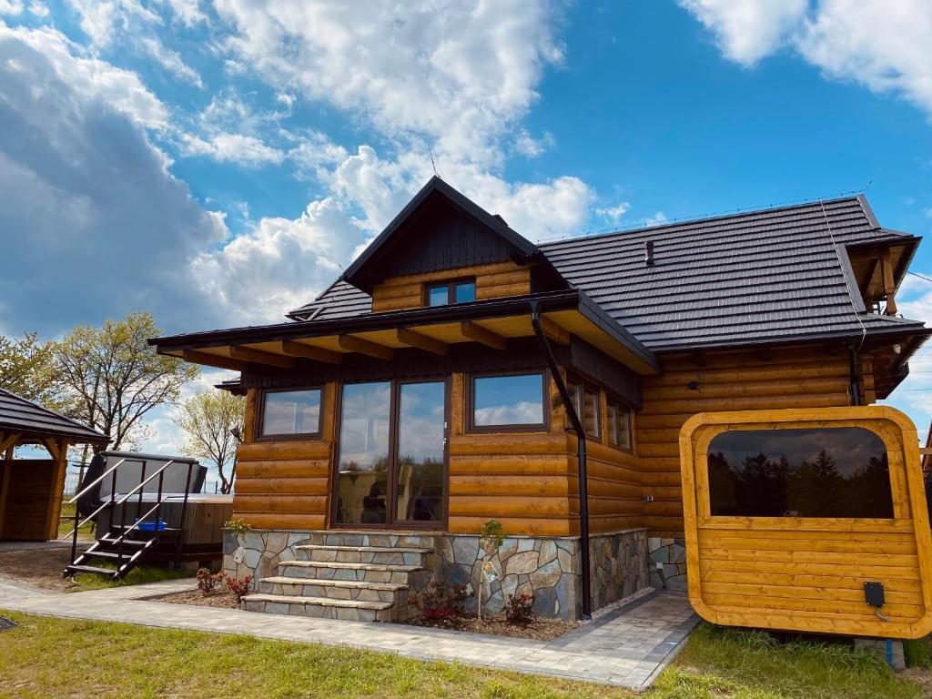 a log cabin with a large window and a house at Apartamenty Arkadia Jaworzynka - Zapasieki in Jaworzynka