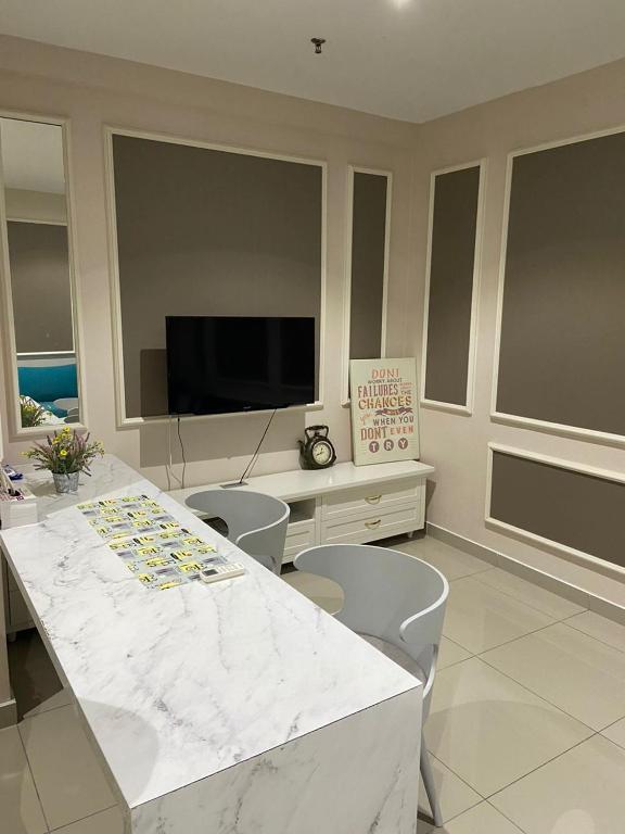 uma sala de estar com mesa, cadeiras e televisão em Orak Villa @ I-City Golden Triangle em Shah Alam