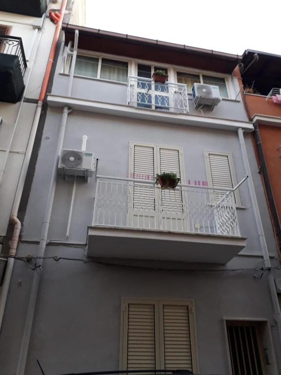 a white apartment building with a balcony and a window at La casa di Ross in Casteldaccia