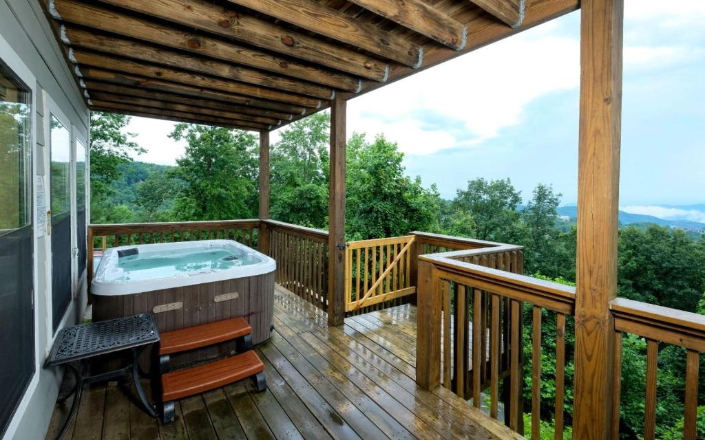 a deck with a jacuzzi tub on a porch at Among The Clouds 2240 in Gatlinburg