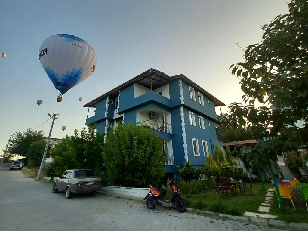 een heteluchtballon die over een blauw huis vliegt bij Paradise Boutique hotel in Pamukkale