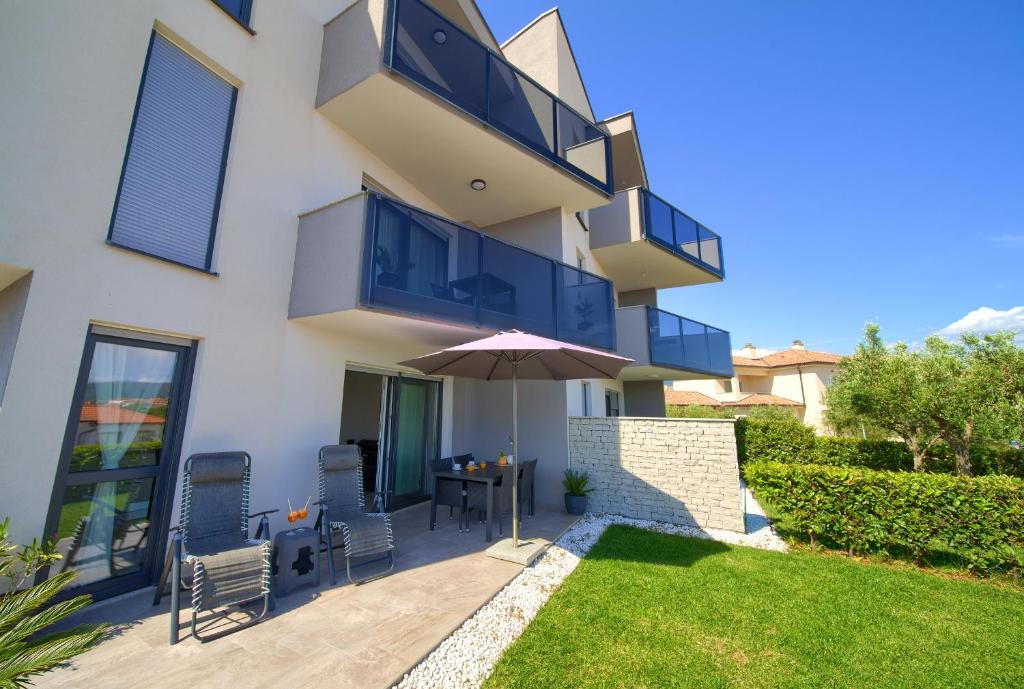 Casa con patio con sombrilla y mesa en Apartment SARA en Krk