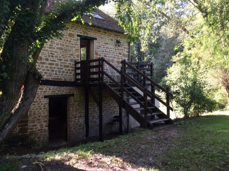 a brick building with a staircase next to a tree at Les Bambous, avec piscine, tennis et lac privatif in Guerquesalles