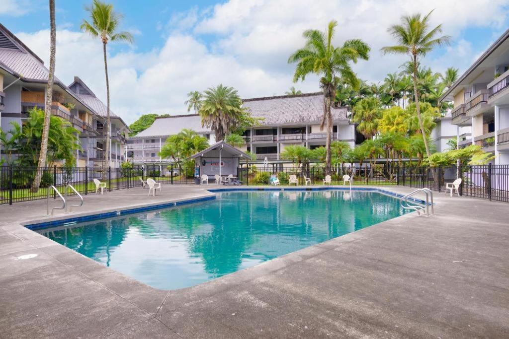 a swimming pool in a courtyard with palm trees at Studio in Hilo Center with Pool and Lake Views in Hilo