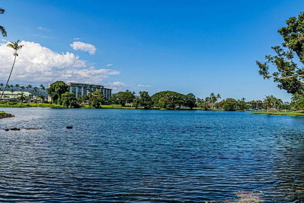 a large lake with trees and a building in the background at Studio in Hilo Center with Pool and Lake Views in Hilo