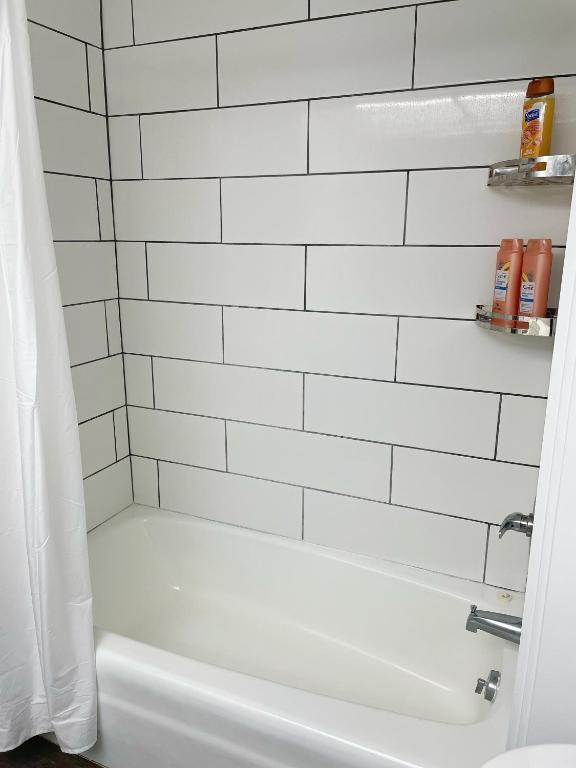 a white tiled bathroom with a white bath tub at Studio in Hilo Center with Pool and Lake Views in Hilo