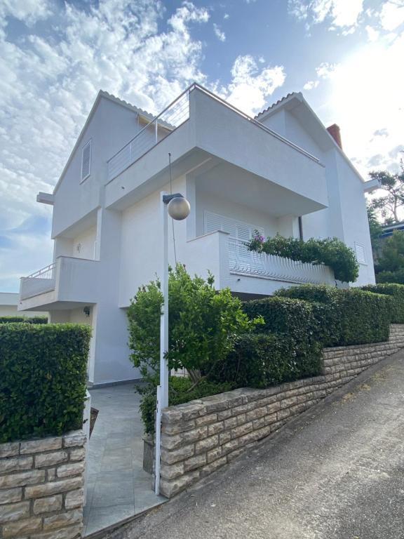 een wit huis met een bakstenen muur bij Red Hill Beach House - stunning 3-story residence in Zaboric