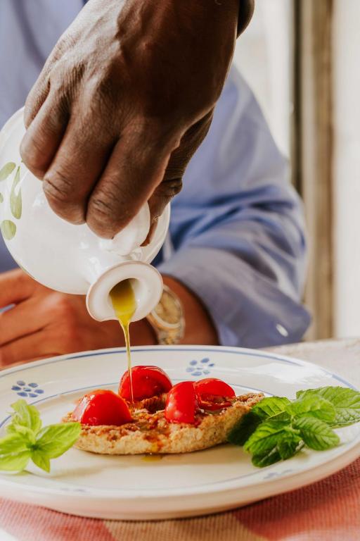 a person pouring sauce on a pizza on a plate at Masseria della Piana in Villanova di Ostuni