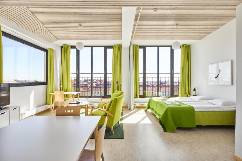 Habitación de hotel con cama verde y ventanas grandes. en Töölö Towers en Helsinki