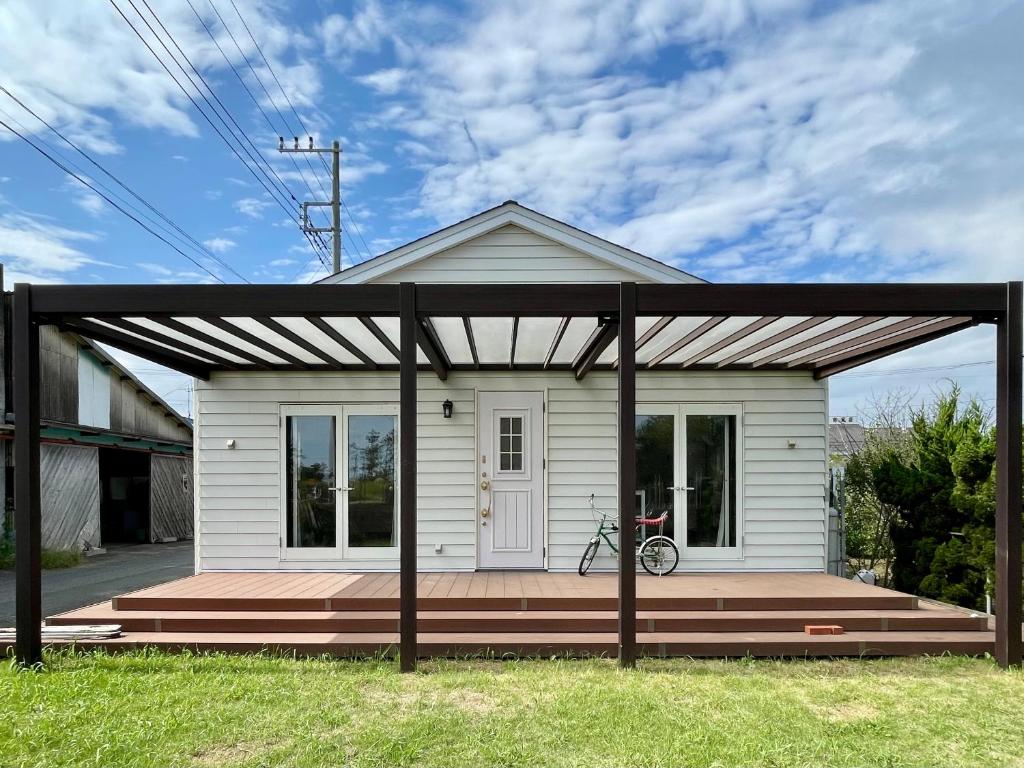 a small white house with a wooden porch at Surf Cottage KATAKAI-九十九里 片貝海岸- in Kujukuri