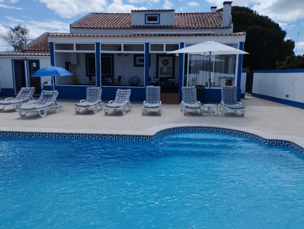 a pool with chairs and umbrellas next to a house at Monte Sol Nascente (Loft) in Grândola
