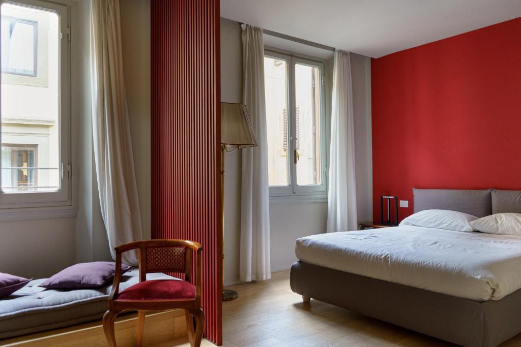 a bedroom with red walls and a bed and a chair at Signoria n&deg;5 in Florence