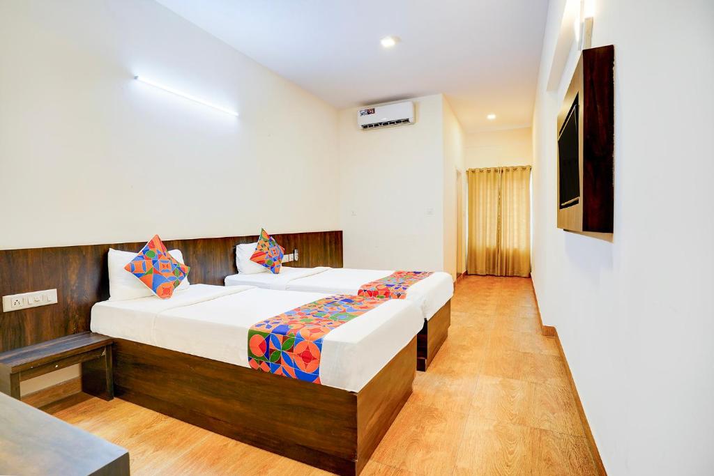 una camera d'albergo con due letti e una televisione di FabHotel GRK Comforts a Bangalore
