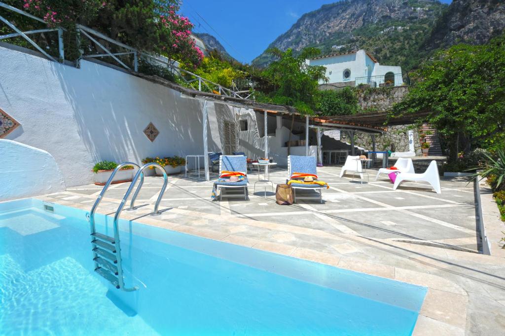 a swimming pool with chairs next to a mountain at Villa Cala del Marò in Praiano