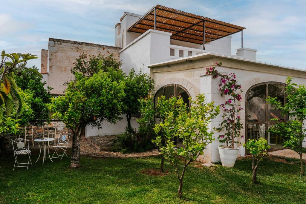 a house with a yard with trees and chairs at Masseria della Piana in Villanova di Ostuni