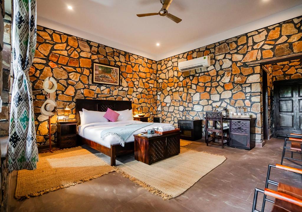 a bedroom with a bed and a stone wall at Moustache Ranthambore Luxuria in Sawāi Mādhopur