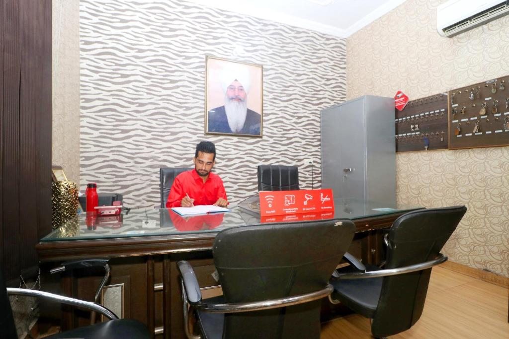 a man sitting at a desk in an office at OYO Flagship Sangam Resort in Shāhpur