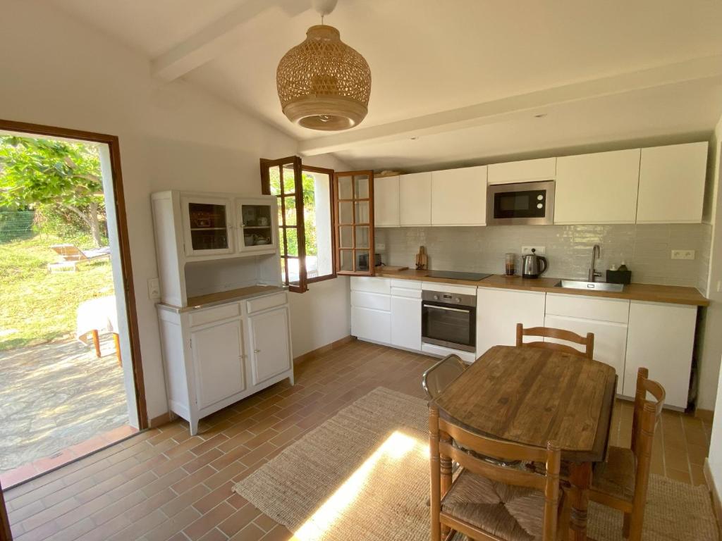 une cuisine avec des armoires blanches et une table en bois dans l'établissement Collinette des Lecques, à Saint-Cyr-sur-Mer