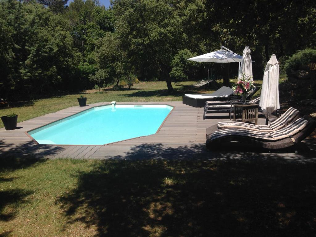 une piscine avec deux chaises et un parasol dans l'établissement Villa provençale entre Aix en Provence et Luberon, à Rognes