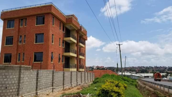 a red brick building on the side of a road at Durlan metroplex in Kampala