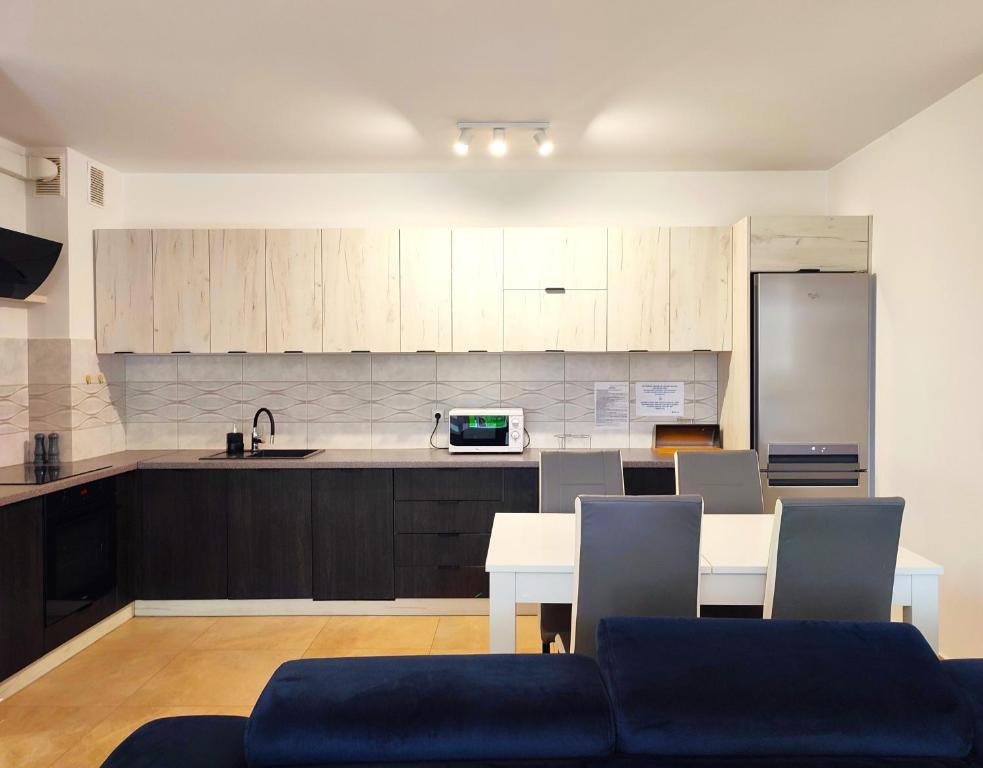 uma cozinha com mesa e cadeiras e uma cozinha com armários brancos em Apartament Warneńczyka Mielec em Mielec