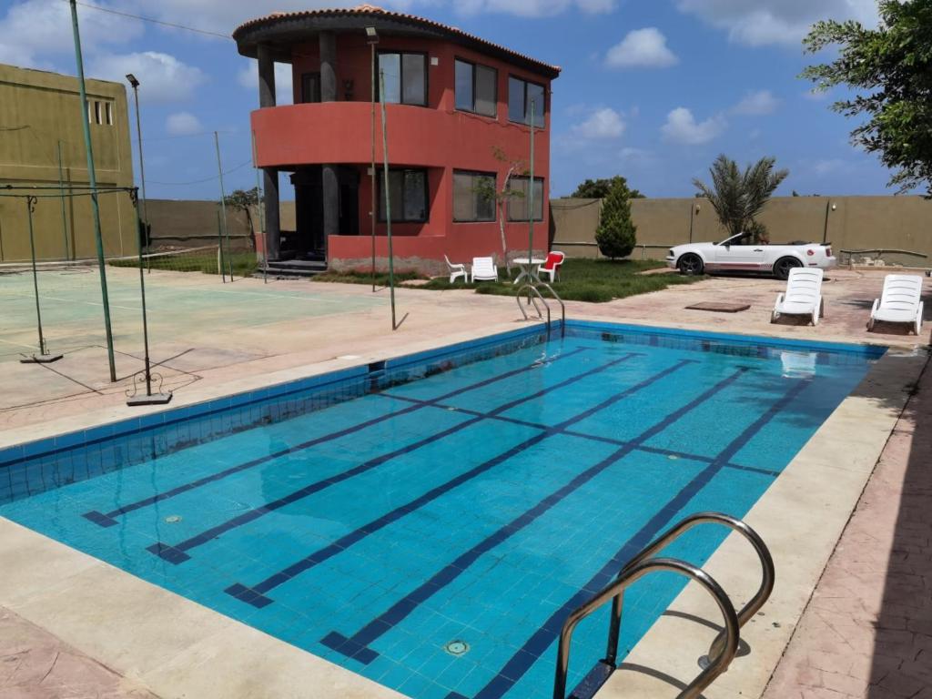 a swimming pool in front of a building at Villa Mostafa Sadek, Swimming pool, Tennis & Squash - Borg ElArab Airport Alexandria in Borg El Arab