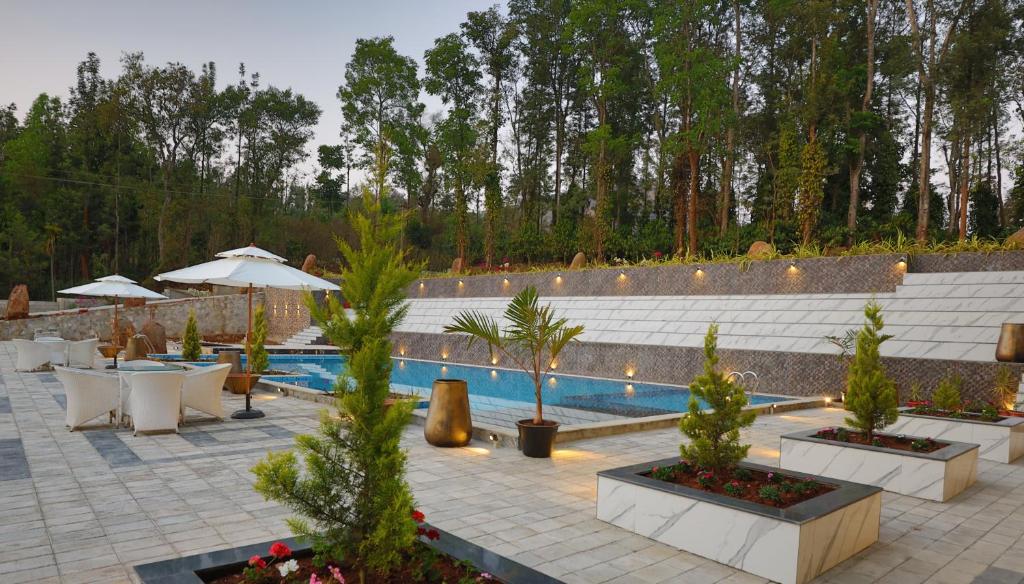 a swimming pool with tables and trees and a resort at The Grand Retreat - Chikmagalur in Chikmagalūr