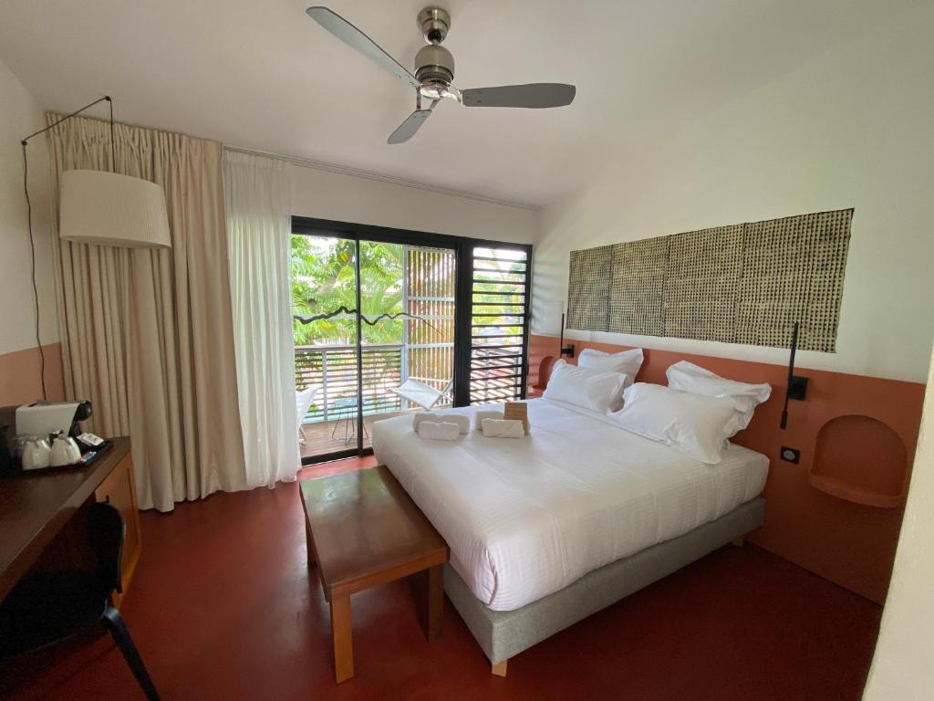 Un dormitorio con una gran cama blanca y una ventana en Dimitile Hôtel & Spa, en Entre-Deux