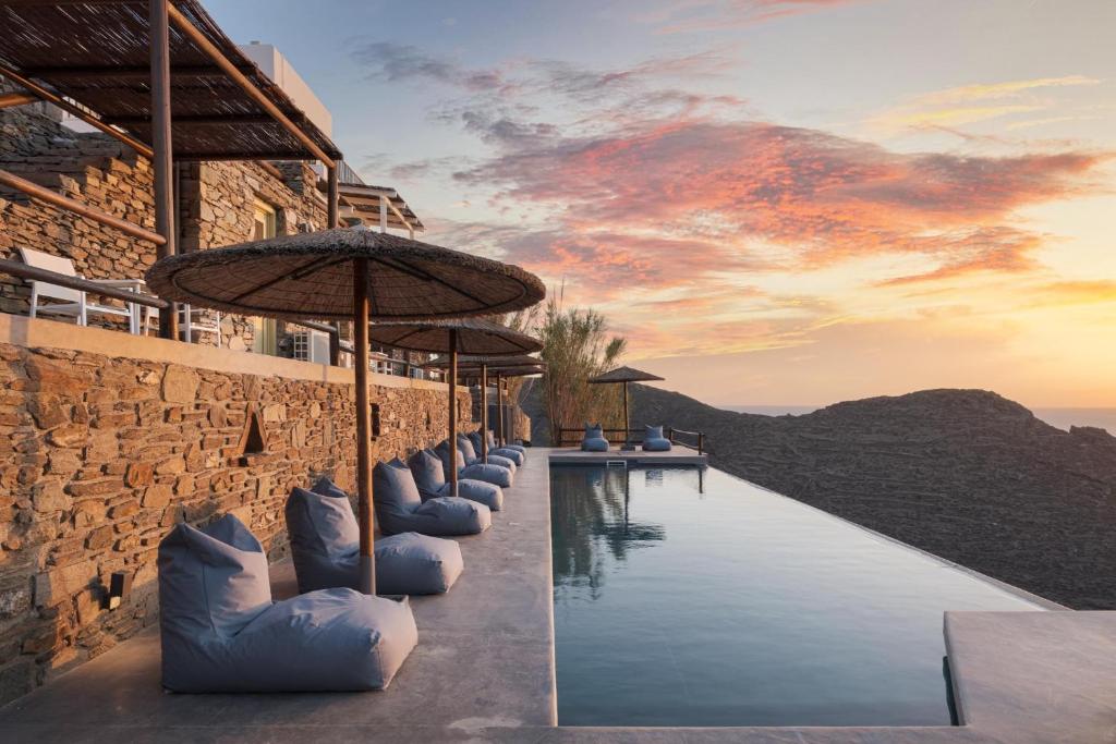 a pool with umbrellas next to a building at Kastella Sunset Villa Four in Kithnos