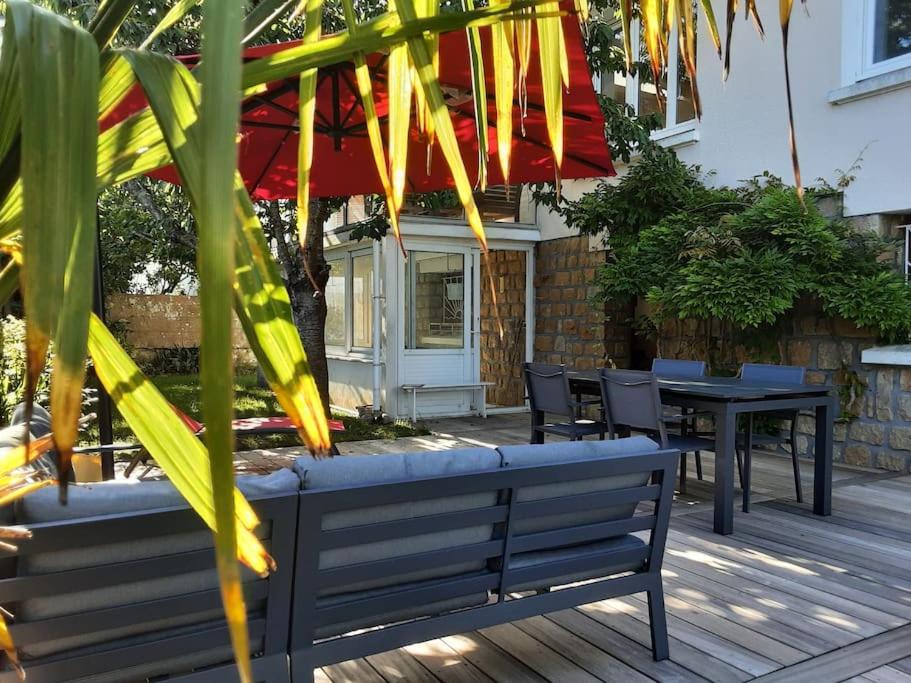 a wooden deck with benches and tables and an umbrella at Le Plongeoir in Donville-les-Bains