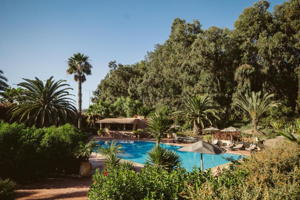 een zwembad met palmbomen en een resort bij Dar Maktoub in Agadir