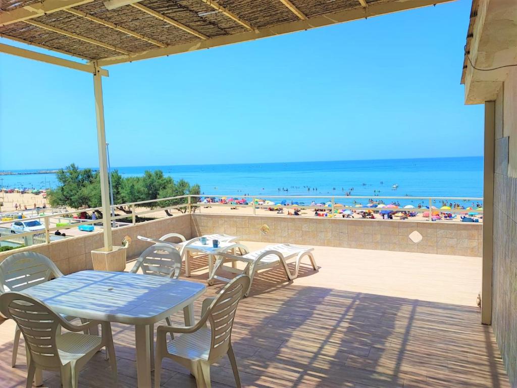eine Terrasse mit Tischen und Stühlen und Blick auf den Strand in der Unterkunft Gambusia in Scoglitti