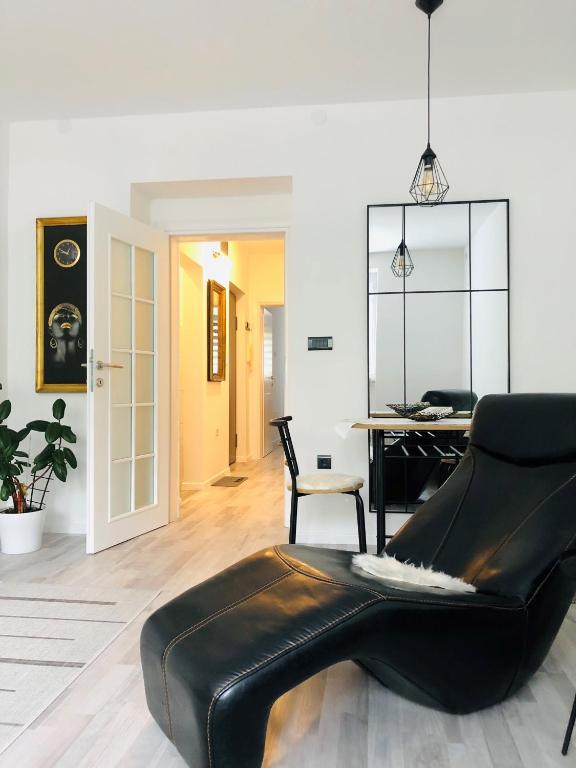 a black leather chair in a room with a table at Centar City Sarajevo Apartman in Sarajevo