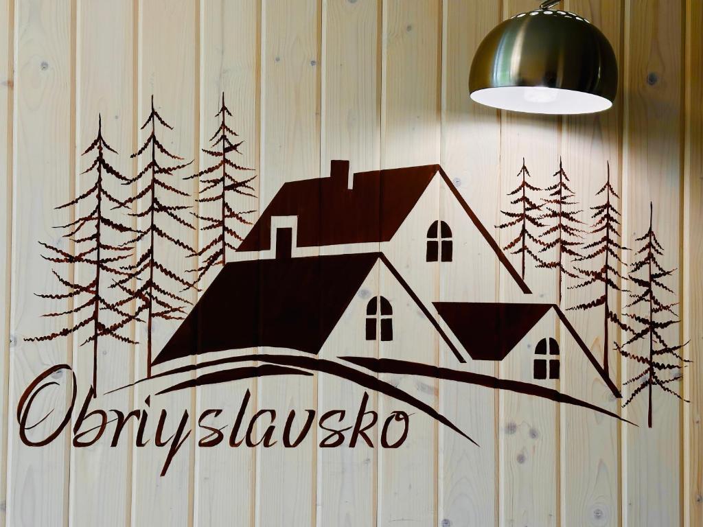 um sinal numa parede com uma casa em Obriyslavsko em Slavske