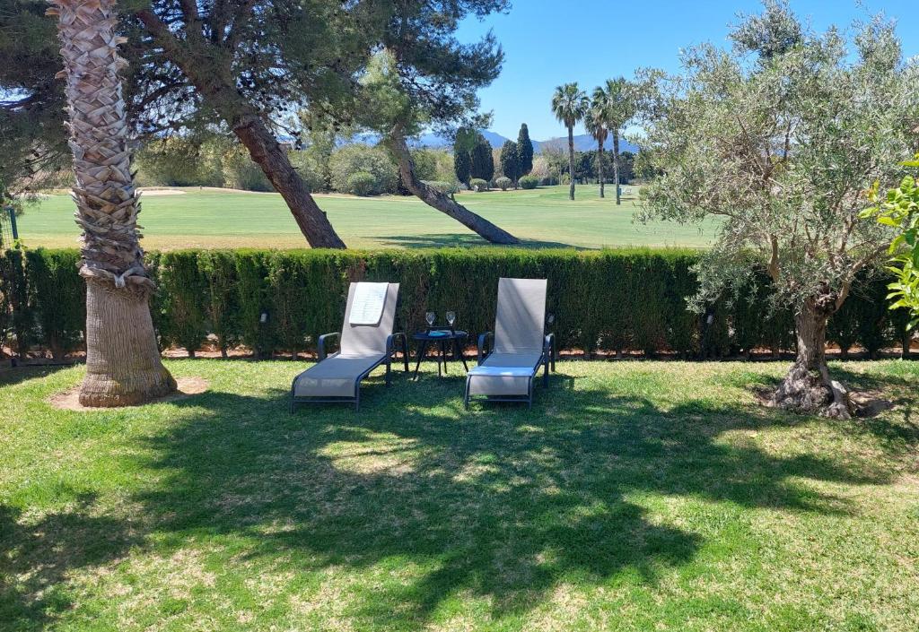 dos sillas y una mesa en un patio con árboles en OLIVA NOVA, playa, jardín, piscina, golf, MET, IDEAL FAMILIAS, en Oliva