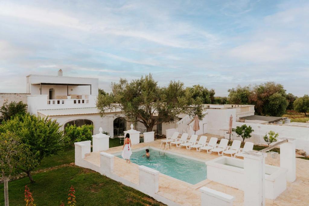 a woman standing in a pool next to a house at Masseria della Piana in Villanova di Ostuni