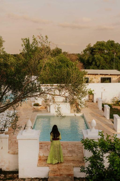 a woman in a green dress standing in front of a pool at Masseria della Piana in Villanova di Ostuni