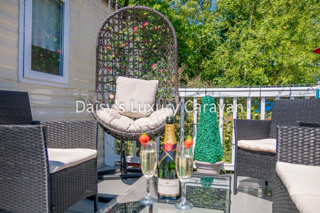 un tavolo con bottiglie di vino e una sedia sul patio di Daisy's luxury caravan at tattershall lakes a Lincoln