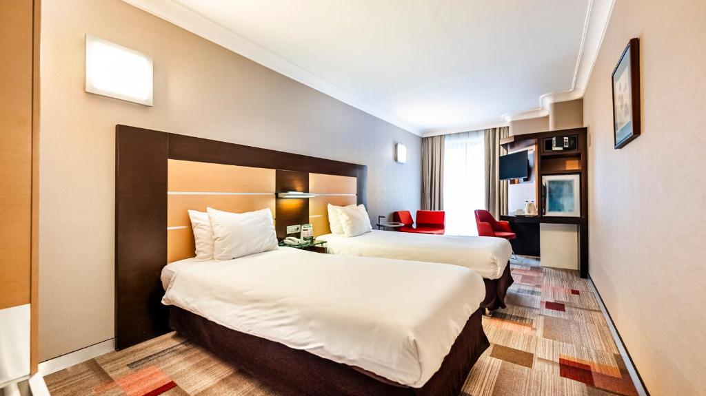 ein Hotelzimmer mit 2 Betten und einem roten Stuhl in der Unterkunft Lamartine Hotel in Istanbul