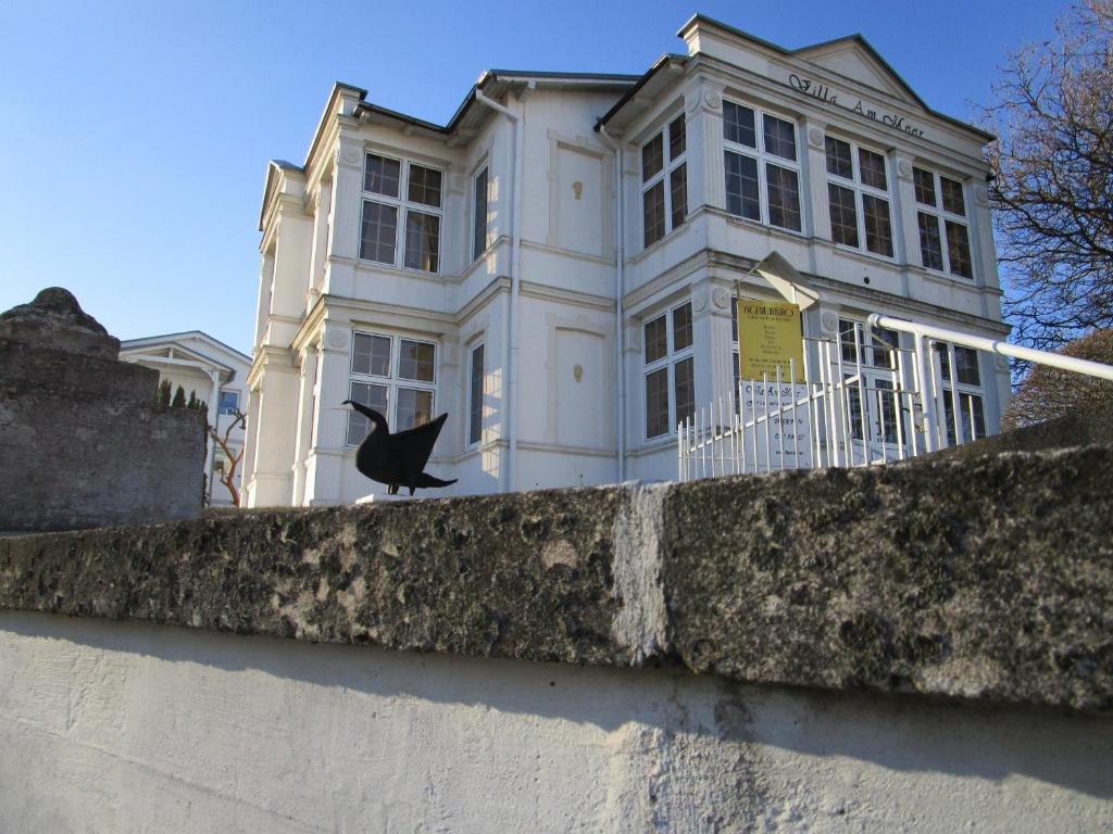 a bird sitting on a wall in front of a house at Villa Am Meer EG2 in Göhren