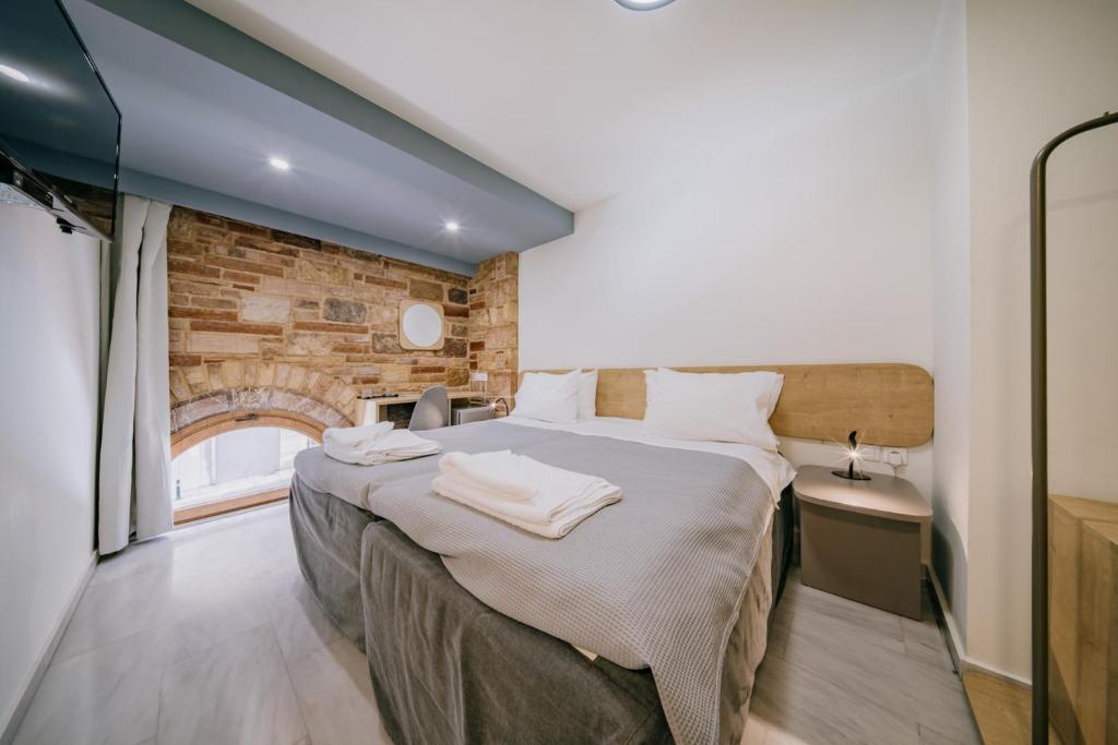 a bedroom with a large bed and a brick wall at Chios City Inn in Chios