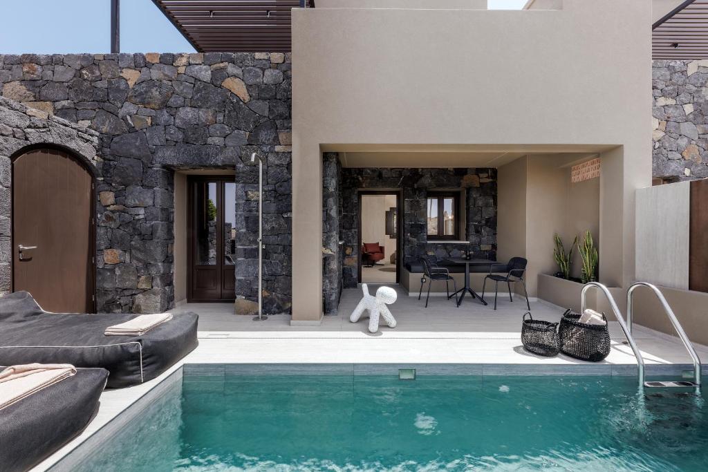 a house with a swimming pool next to a stone wall at Hidden Hills in Mesaria