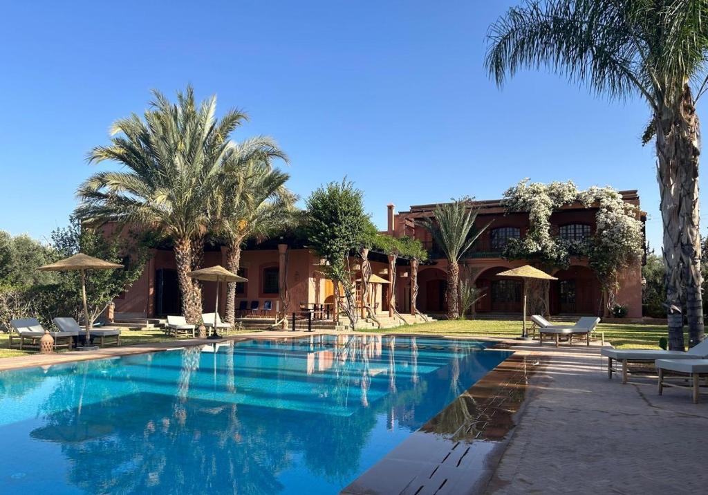 une piscine devant une maison avec des palmiers dans l'établissement Villa Keshmere, à Marrakech