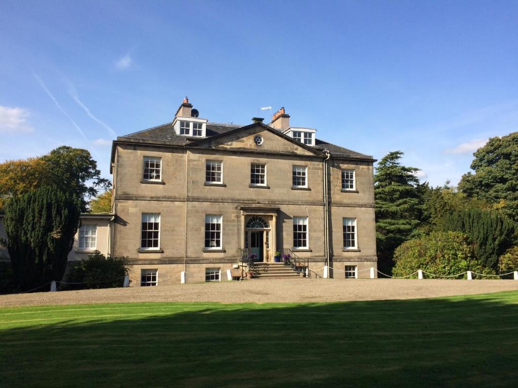 una casa antigua con un gran campo de hierba delante en Limefield House, en Livingston