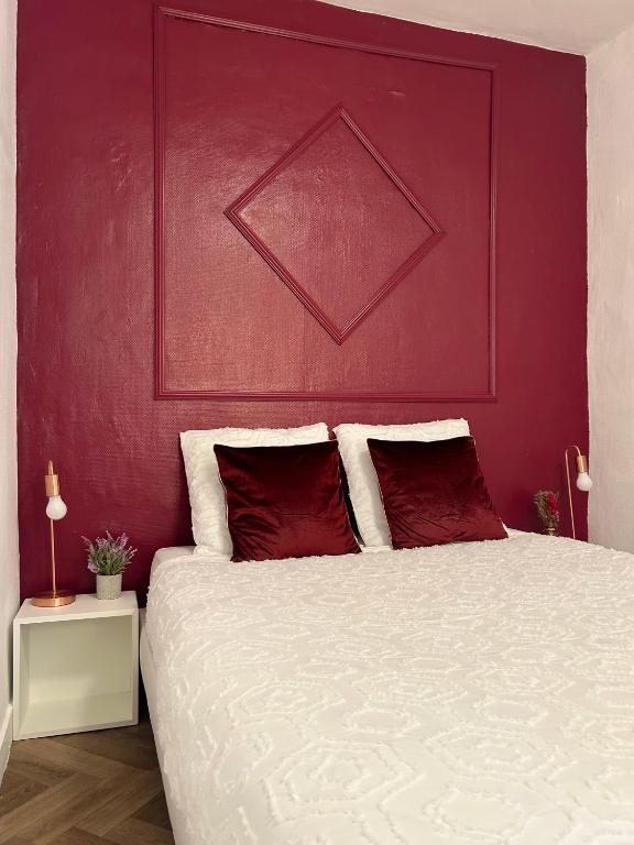 une chambre avec un grand lit avec un mur rouge dans l'établissement Aurore - Château de Versailles - Central, à Versailles
