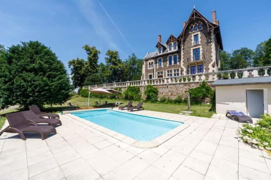 a swimming pool in front of a large house at Manoir des Rêves Sauvages in Parentignat