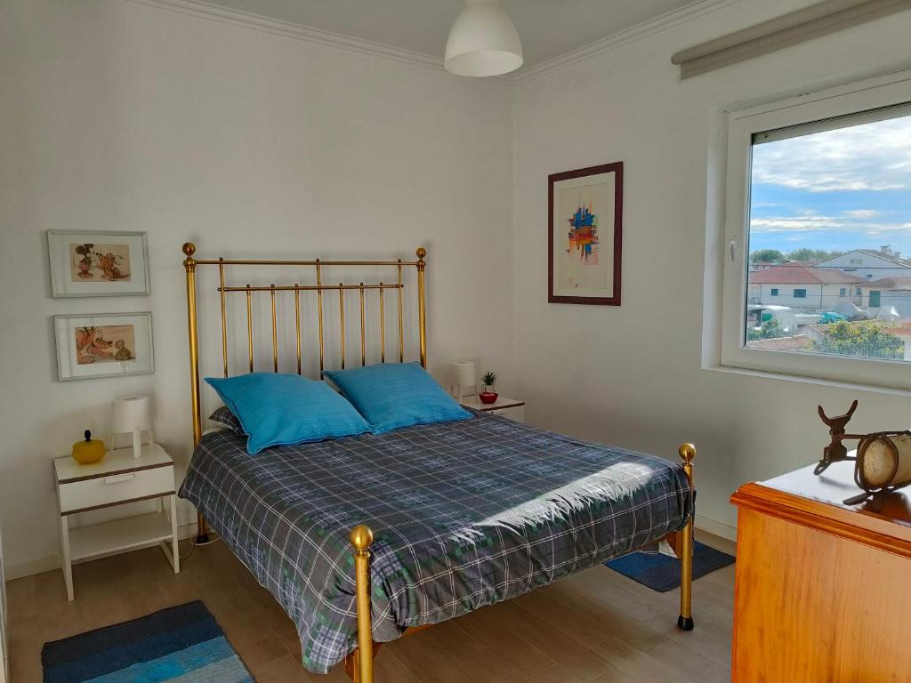 a bedroom with a bed with blue pillows and a window at Casa da Ilha dos Ovos in Aveiro