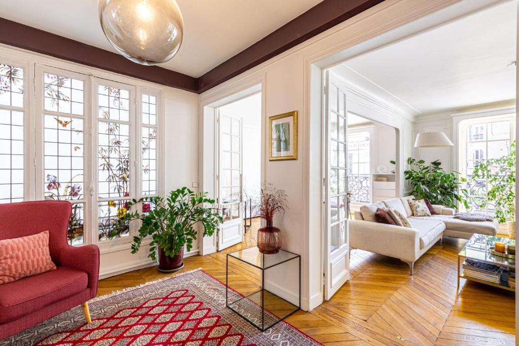un salon avec une chaise rouge et un canapé dans l'établissement GuestReady - Grand apt lumineux à Montmartre, à Paris